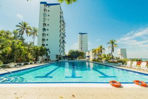 a large swimming pool with palm trees and buildings at Paraíso By Elemnt Rentals in Santa Marta