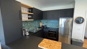 a kitchen with black cabinets and a stainless steel refrigerator at Higgi Drive 6 in Mount Hotham