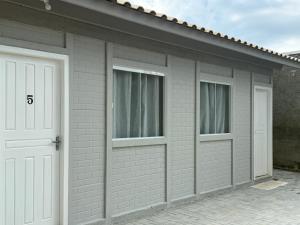 a garage with two white doors and two windows at Casa nova bem aconchegante e tranquila in Biguaçu