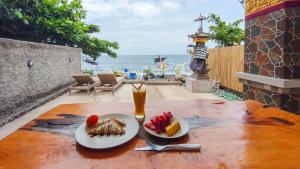 a table with two plates of food and a drink at Dewata Beach House in Amed