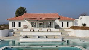 a house with a swimming pool in front of a house at Kadamb Bagh-A Luxury Nature Resort Sariska in Rāmsinghpura