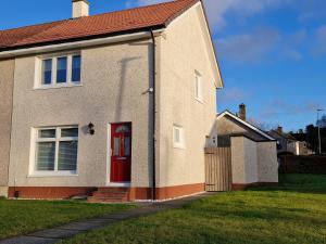 a house with a red door and a fence at Justina's House in East Kilbride