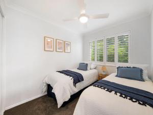 two beds in a room with white walls and a window at Seabreeze unit 5, Kings Beach in Caloundra