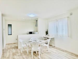 a white dining room with a table and chairs at Villa 勝浦 in Katsuura