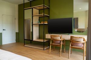 a room with a desk with two chairs and a flat screen tv at Reach Home Hatyai in Hat Yai