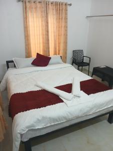 a bedroom with a large bed with red and white sheets at ACK River Palms - Athirappilly in Athirappilly