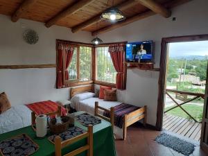 a living room with a bed and a table and a television at Cabañas Mónika IV Sur in Huerta Grande