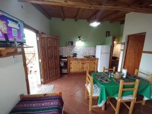 a kitchen with a green table with chairs and a refrigerator at Cabañas Mónika IV Sur in Huerta Grande