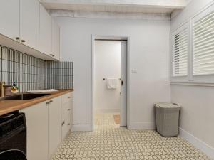 a kitchen with white cabinets and a sink and a door at Sea Side Glide at Maloneys Hide in Maloney's Beach +28 photos