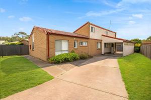 a brick house with a driveway in a yard at Sea Side Glide at Maloneys Hide in Maloney's Beach