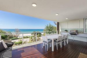a living room with a table and chairs on a balcony at Waves #9 by Discover Stradbroke in Point Lookout