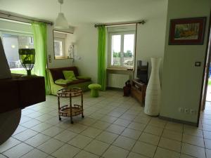 a living room with green curtains and a chair at L'étable aux deux noix in Arc-en-Barrois