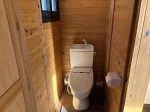 a small bathroom with a toilet in a wooden room at Costa Hinase Resort in Kakui-jima