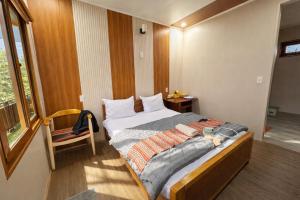 a bedroom with a bed and a chair and a window at Ngọc Trâm Homestay in A Lưới (1)