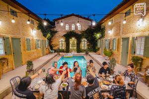 a group of people sitting at a table in front of a pool at SATTAHIP Zentobu House in Ban Tao Than