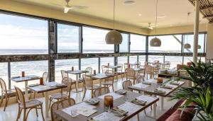 a restaurant with tables and chairs and a view of the ocean at Beach Side Getaway Lighthouse Beach in East Ballina