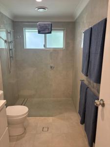 a bathroom with a toilet and a shower with blue towels at Beach Side Getaway Lighthouse Beach in East Ballina +7 photos