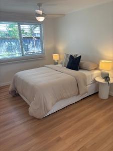 a white bedroom with a large bed with two lamps at Beach Side Getaway Lighthouse Beach in East Ballina