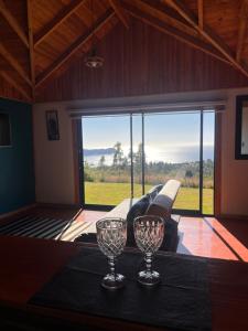 two wine glasses on a table in a room with a couch at Cabaña arriendo Salome in Valdivia