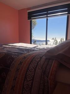 a bedroom with a bed and a large window at Cabaña arriendo Salome in Valdivia +8 photos