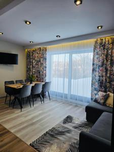 a living room with a table and chairs and a large window at Domki Leśne Zacisze in Baczyn