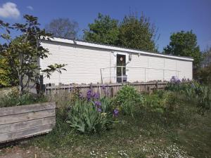 a white building with a red door in a garden at Camping Beausejour Sergines in Sergines