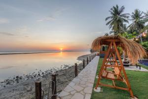a ladder on the beach with a sunset in the background at La Semaya Beach Villas in Nusa Penida