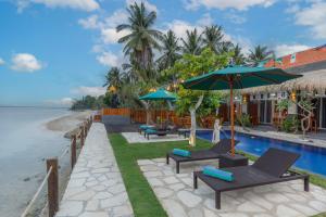 a resort with chairs and umbrellas next to a swimming pool at La Semaya Beach Villas in Nusa Penida