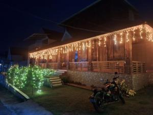 a motorcycle parked in front of a house with christmas lights at Jackroot Heritage wood villa Athirappilly in Kallana +23 photos