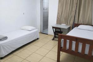 a room with two beds and a table and a desk at Pousada RC Q3 in Várzea Grande