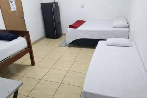 a room with two beds and a refrigerator at Pousada RC Q3 in Várzea Grande