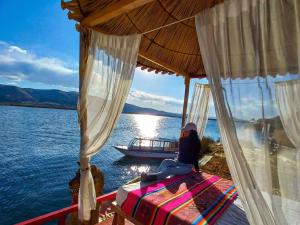 a woman sitting on a bed on a boat in the water at Titicaca Samay Lodge Perú in Puno
