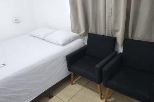 a bed and two chairs in a room at Pousada RC Q2 in Várzea Grande