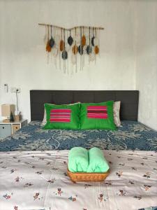 a bed with green pillows and a basket on it at JE Garden Guesthouse in Oecusse RAEOA in Deli