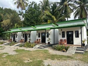 a small white house with chairs and palm trees at JE Garden Guesthouse in Oecusse RAEOA in Deli