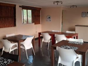 a dining room with two tables and white chairs at Sunset Safari Camp at Hluhluwe Game Park in KwaNompondo