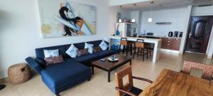 a living room with a blue couch and a kitchen at Nikki Beach Oceanfront Penthouse in Río Hato