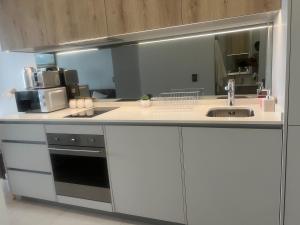 a kitchen with white cabinets and a sink and a mirror at Executive Studio at Ellipse Galileo - Waterfall in Midrand