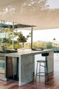 a kitchen with a counter and a stool in a room at Triptych - The Glass House in Koonya