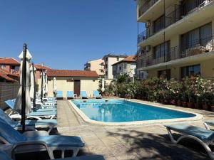 a swimming pool with lounge chairs next to a building at Family Hotel Chris in Sveti Vlas