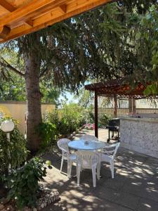 a patio with a table and chairs under a tree at Family Hotel Chris in Sveti Vlas +81 photos
