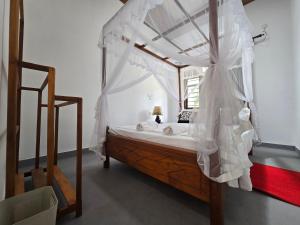 a bedroom with a canopy bed with white curtains at Shayon Villa in Hiriketiya