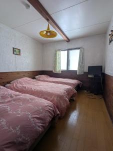 a room with four beds and a television in it at Hachiko Inn in Myoko