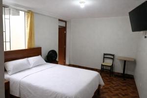 a bedroom with a white bed and a chair at El Sol de Nazca in Nazca
