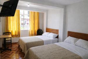 a hotel room with two beds and a television at El Sol de Nazca in Nazca