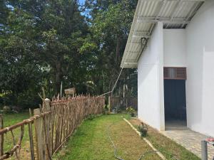 a fence next to a white building with a blue door at Shayon Villa in Hiriketiya