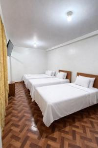 a row of three beds in a room at El Sol de Nazca in Nazca