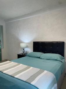 a bedroom with a bed with a black headboard at Hotel Dos Mundos, Isla Cozumel in Cozumel