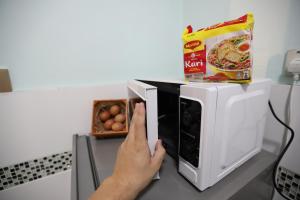a person is putting a box in a microwave at PortDickson Sakura 10Pax 3BR Glory Beach Resort Suite in Port Dickson