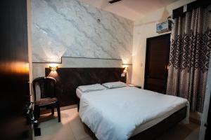 a bedroom with a white bed and a chair at Hotel Blessing Inn in Jalandhar